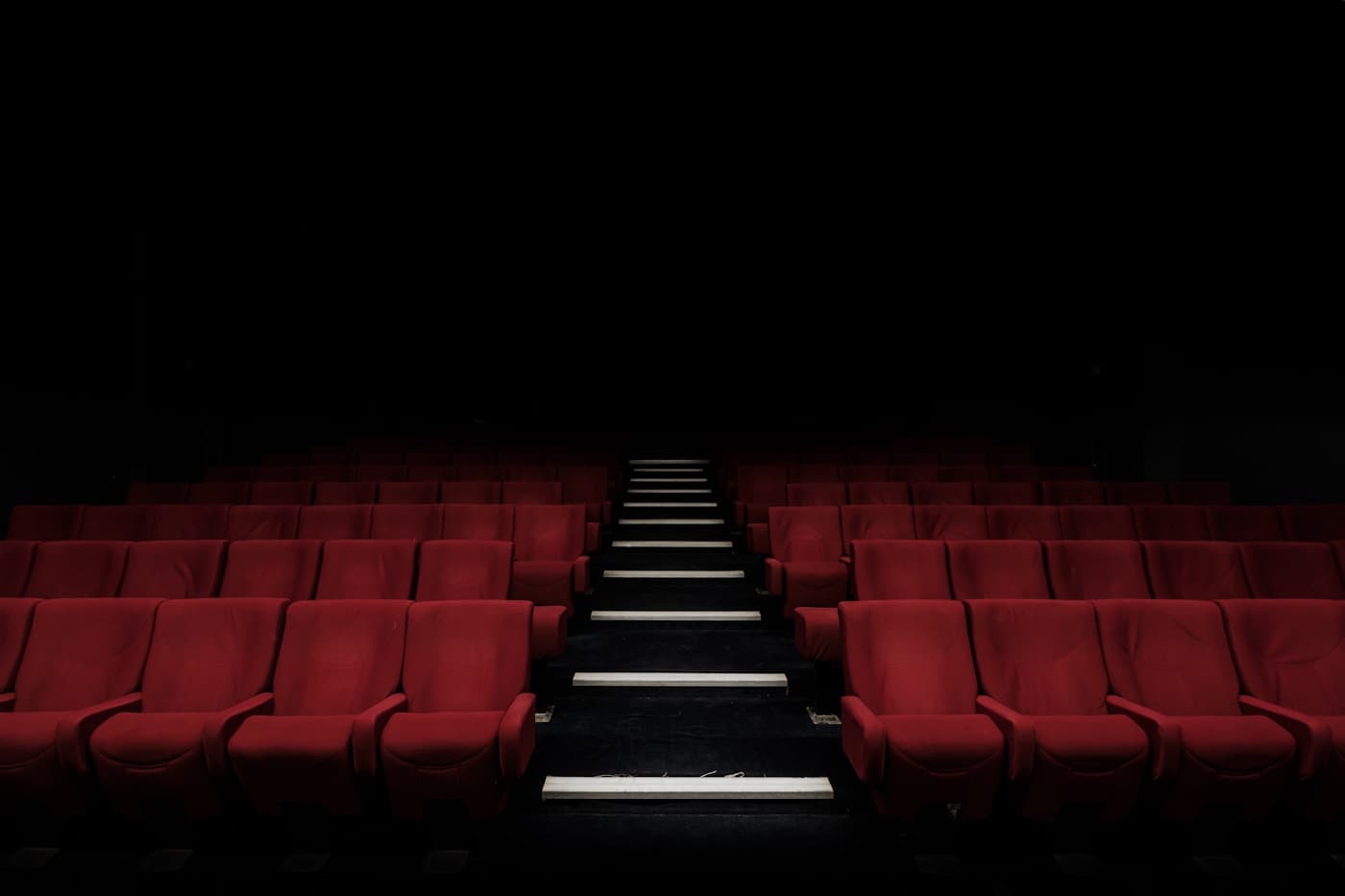 Dark movie theater with rows of red seats